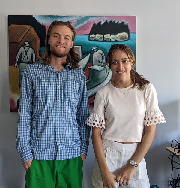 Amy stands next to another person in front of a piece of art.