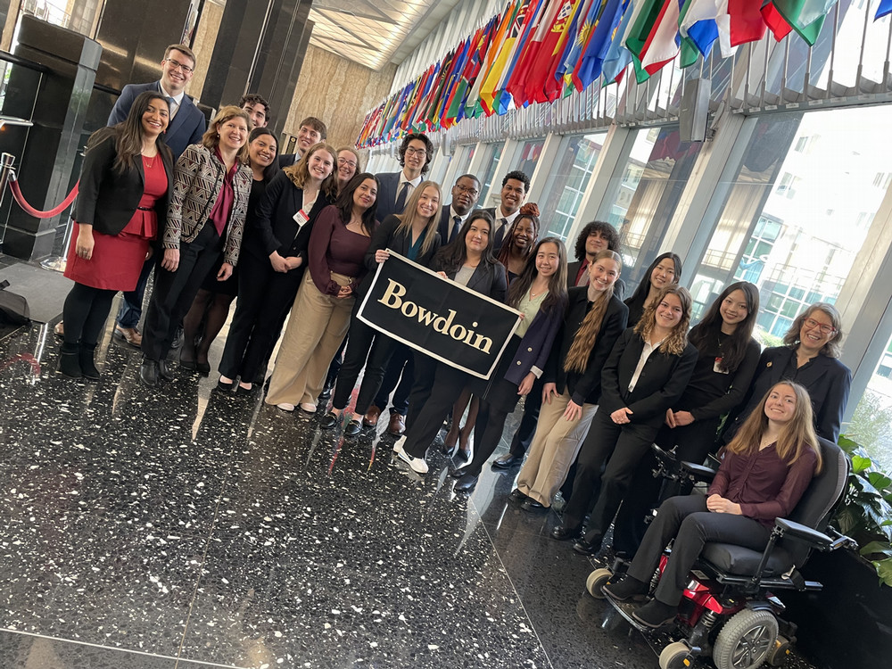 BPS 2024 cohort poses in the State Department holding a Bowdoin flag