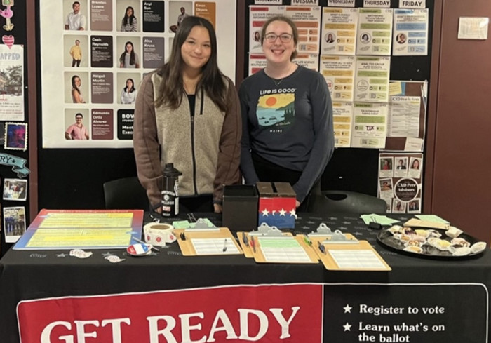 two students standing at Bowdoin Votes registration table