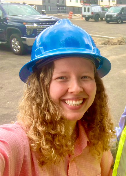 Katie's smiling face. Katie is wearing a construction hat.