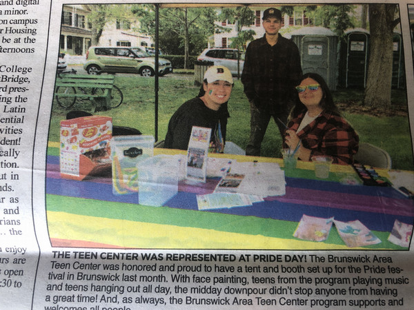 Newspaper clip of Emely sitting with another person at a table under a tent.