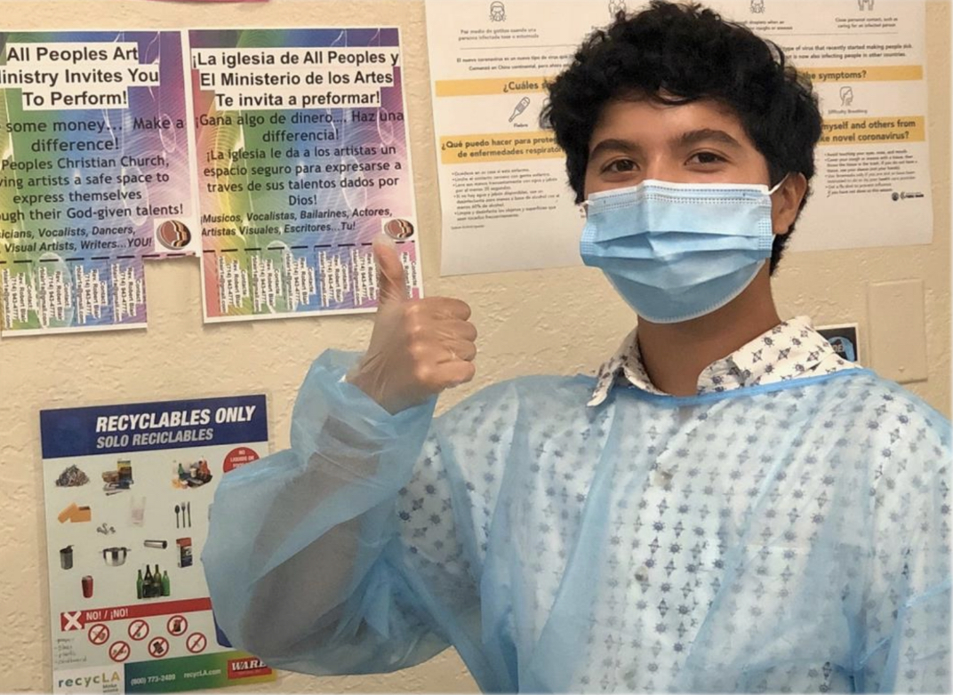 Roman smiling in a hygienic costume while putting his thumbs up.