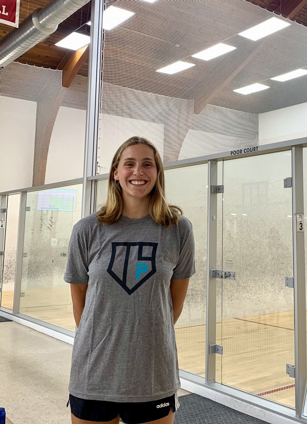 Jess stands by a squash court.