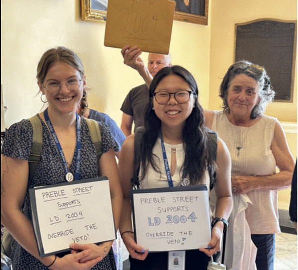 Jiahn stands holding a sign next to two other people.