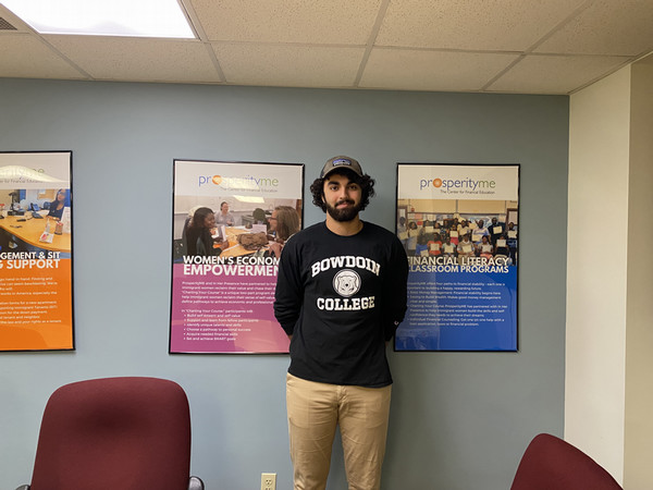 Kavi stands in front of a wall with framed posters on it.