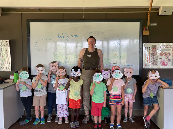 Rory stands with a group of children holding masks in front of their faces.