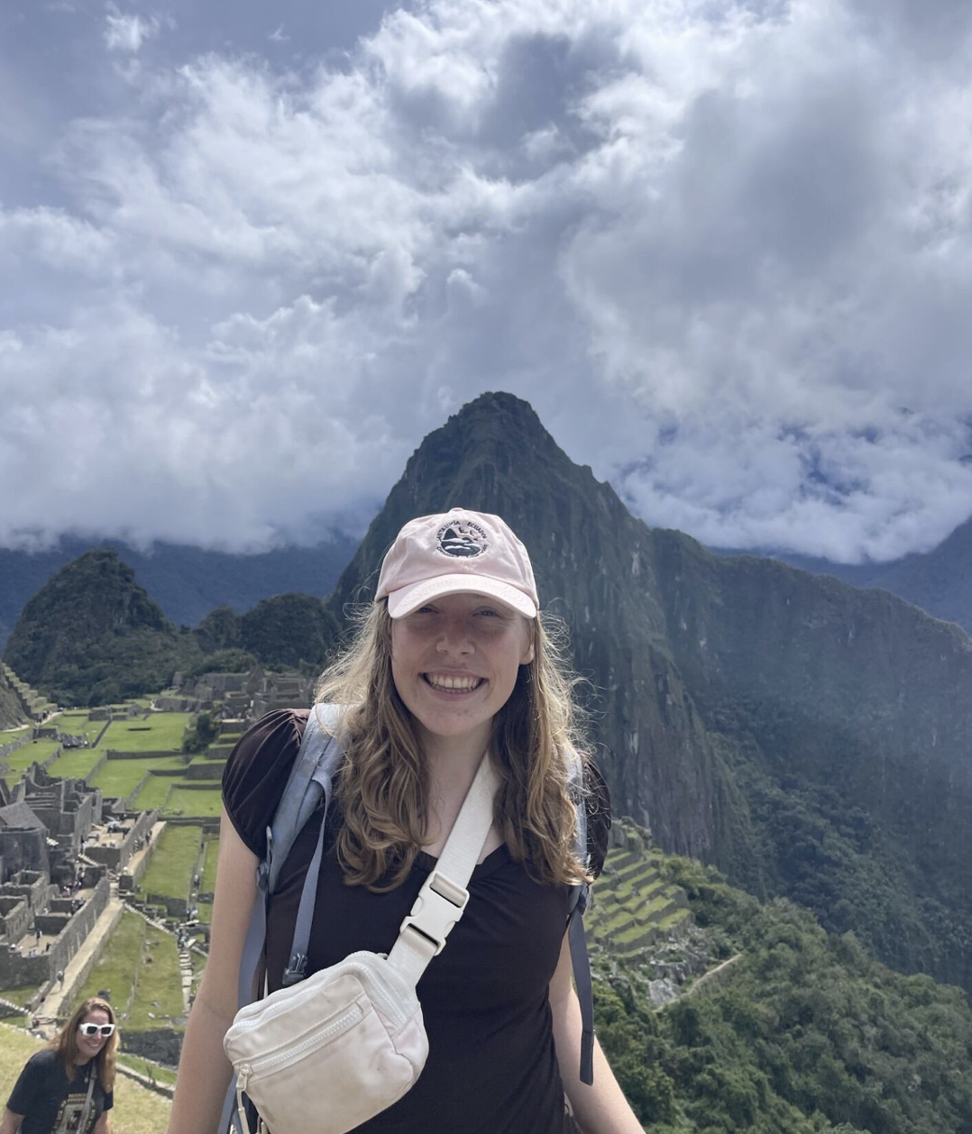 Emma wears a light pink hat and smiles at the camera