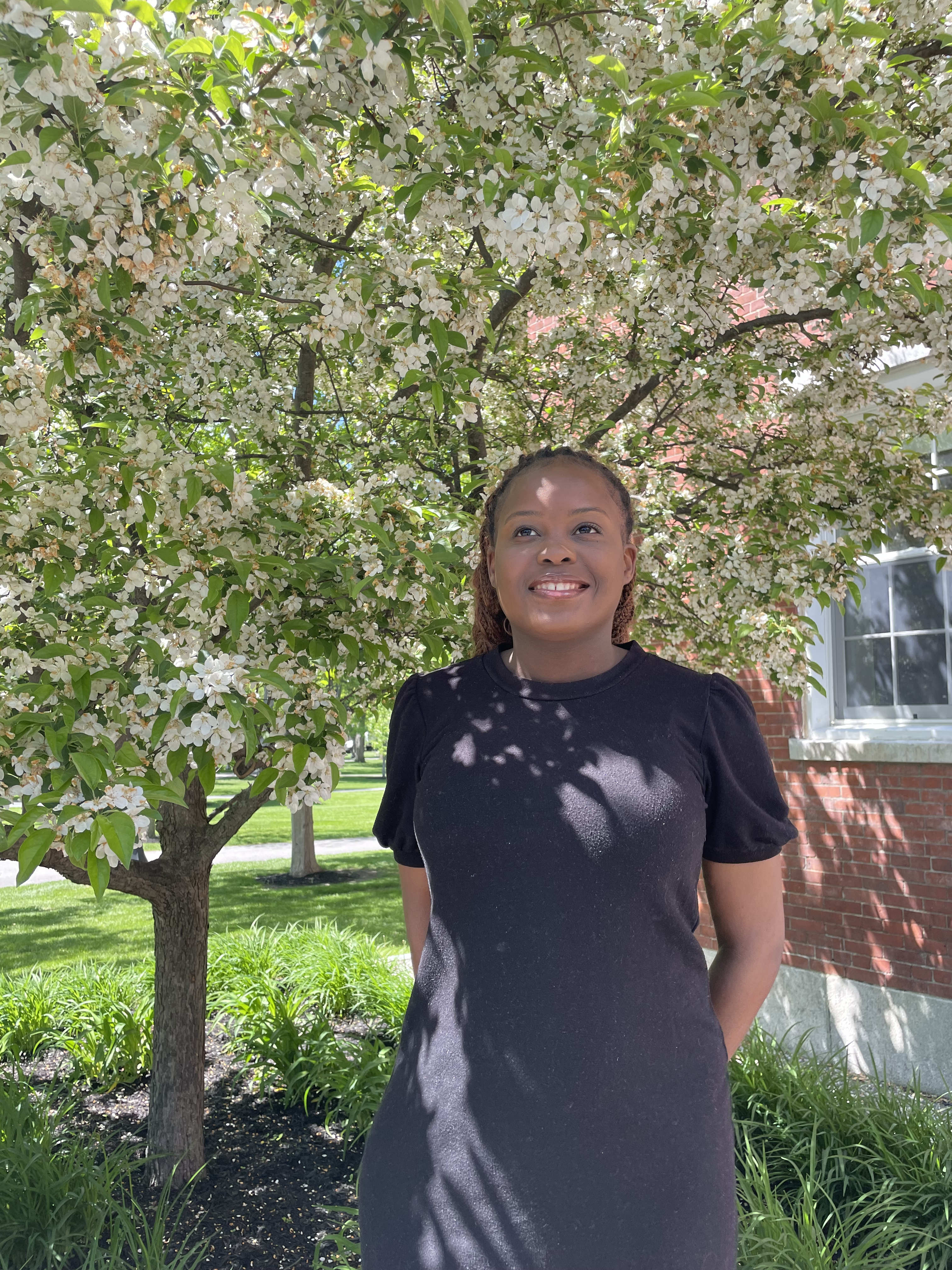 Muku smiles and looks up. Tree in bloom in the background