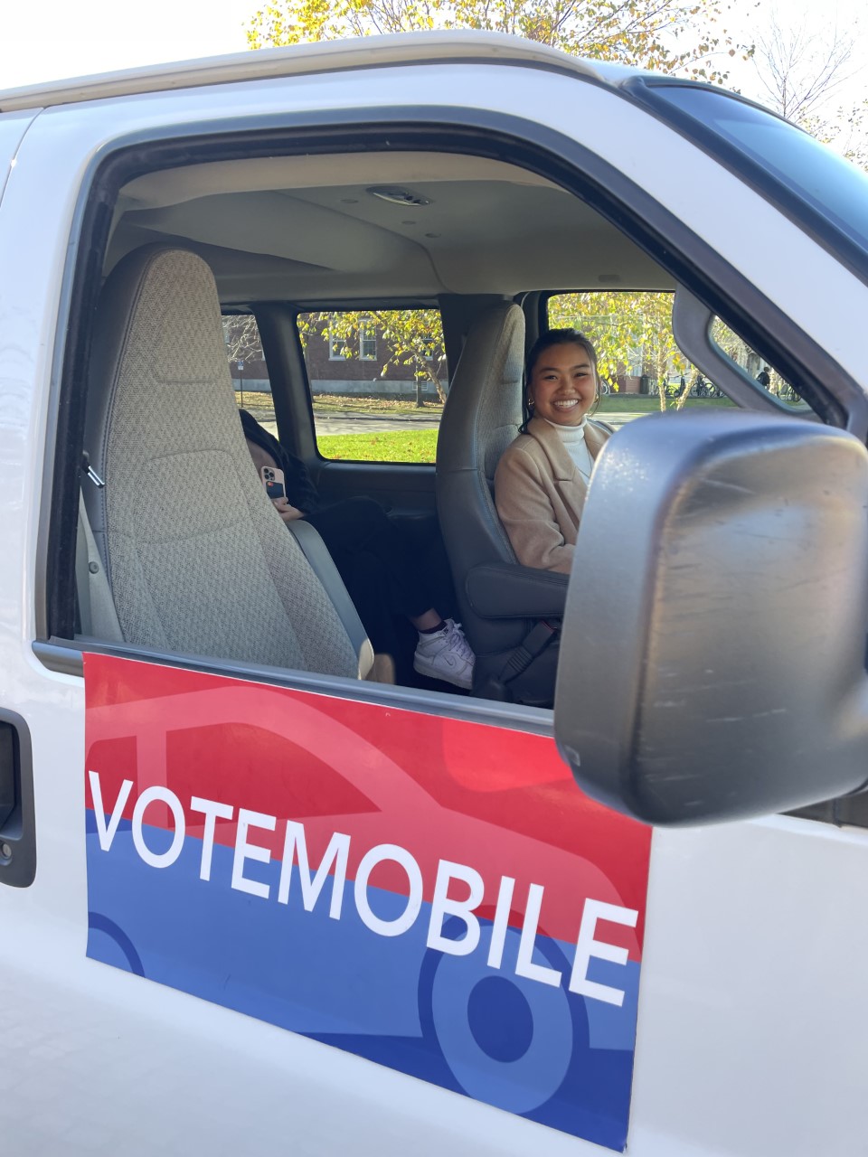 Assistant Director Lynn Nguyen in the driver's seat of a van with a Bowdoin Votes logo on the side.