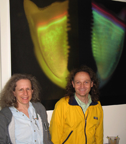 Amy and Olaf in front of a poster-size photo of a marked urchin jaw. Actual size is approximately 3 mm.