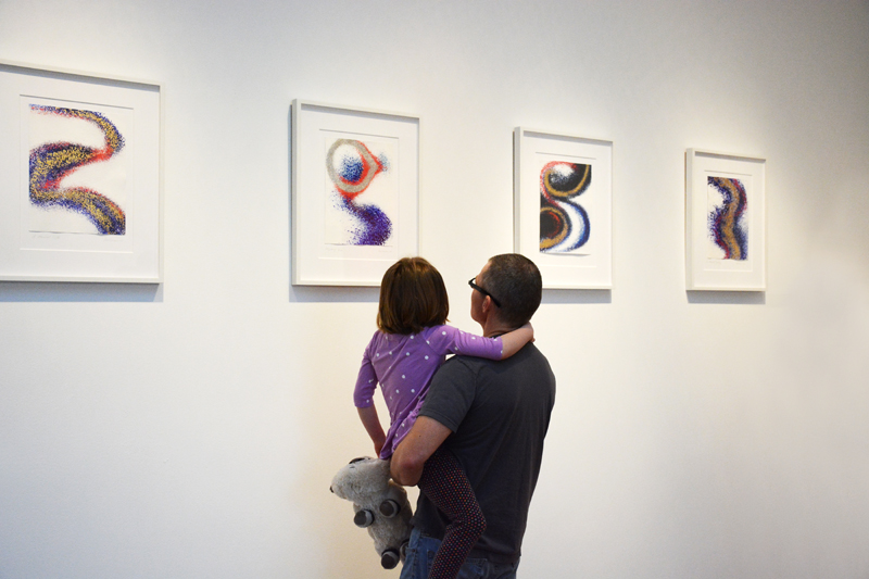 Father and daughter look at art show