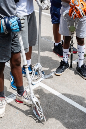 students stand with their lacrosse equipment