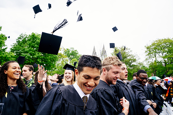 Graduates smiling and throwing graduation caps in the air