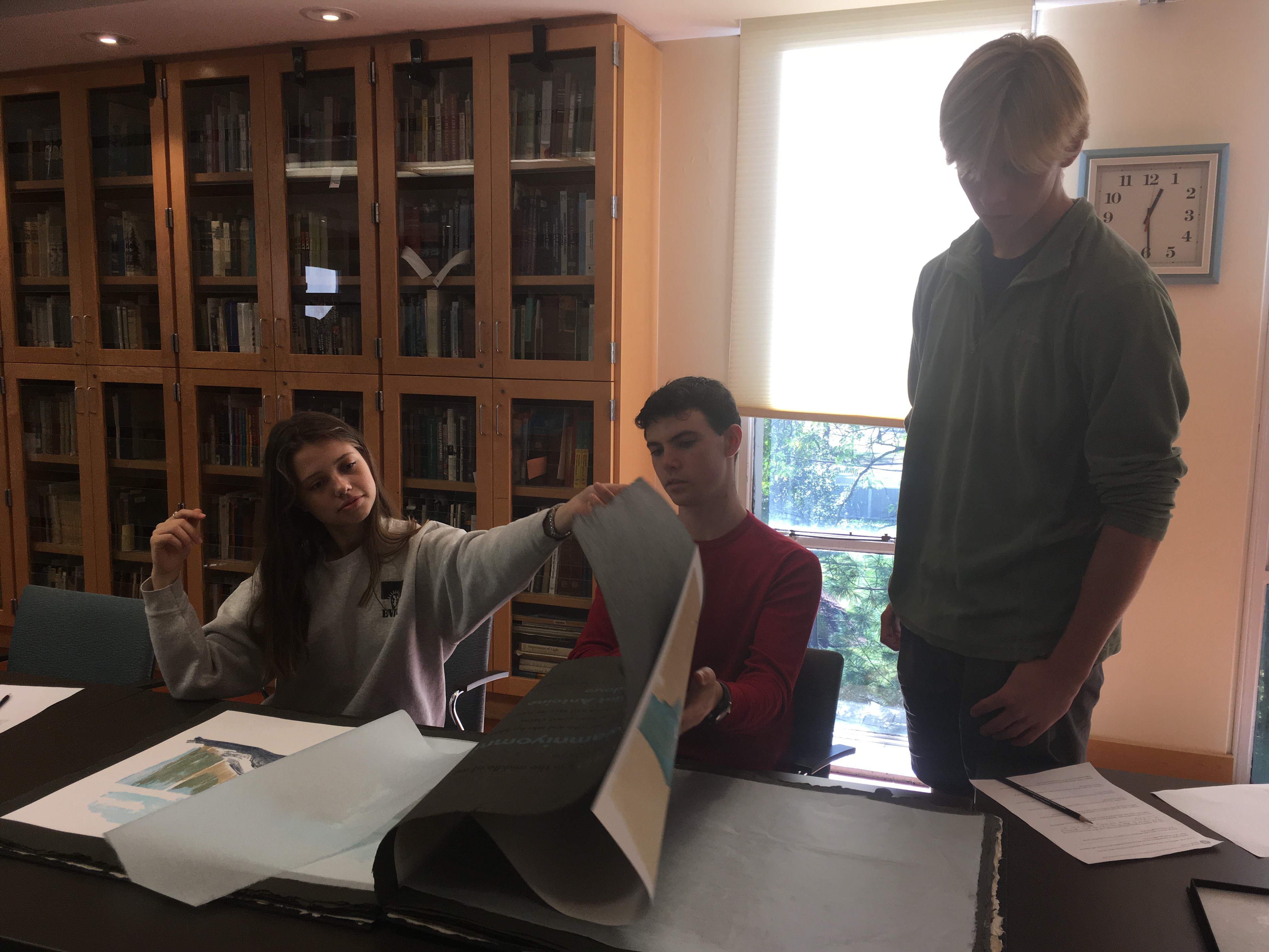 Students in the Introduction to Environmental Studies class page through a large book of Kate Furbish prints.