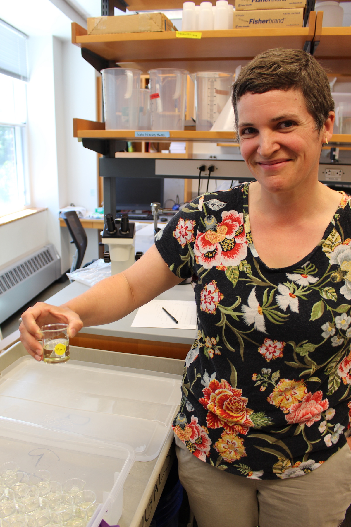 Mary Rogalski with a beaker containing daphnia