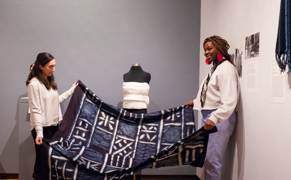 Allison Martino holds up a Ghanaian textile with Anu Asaolu ’19 at the Museum of Art