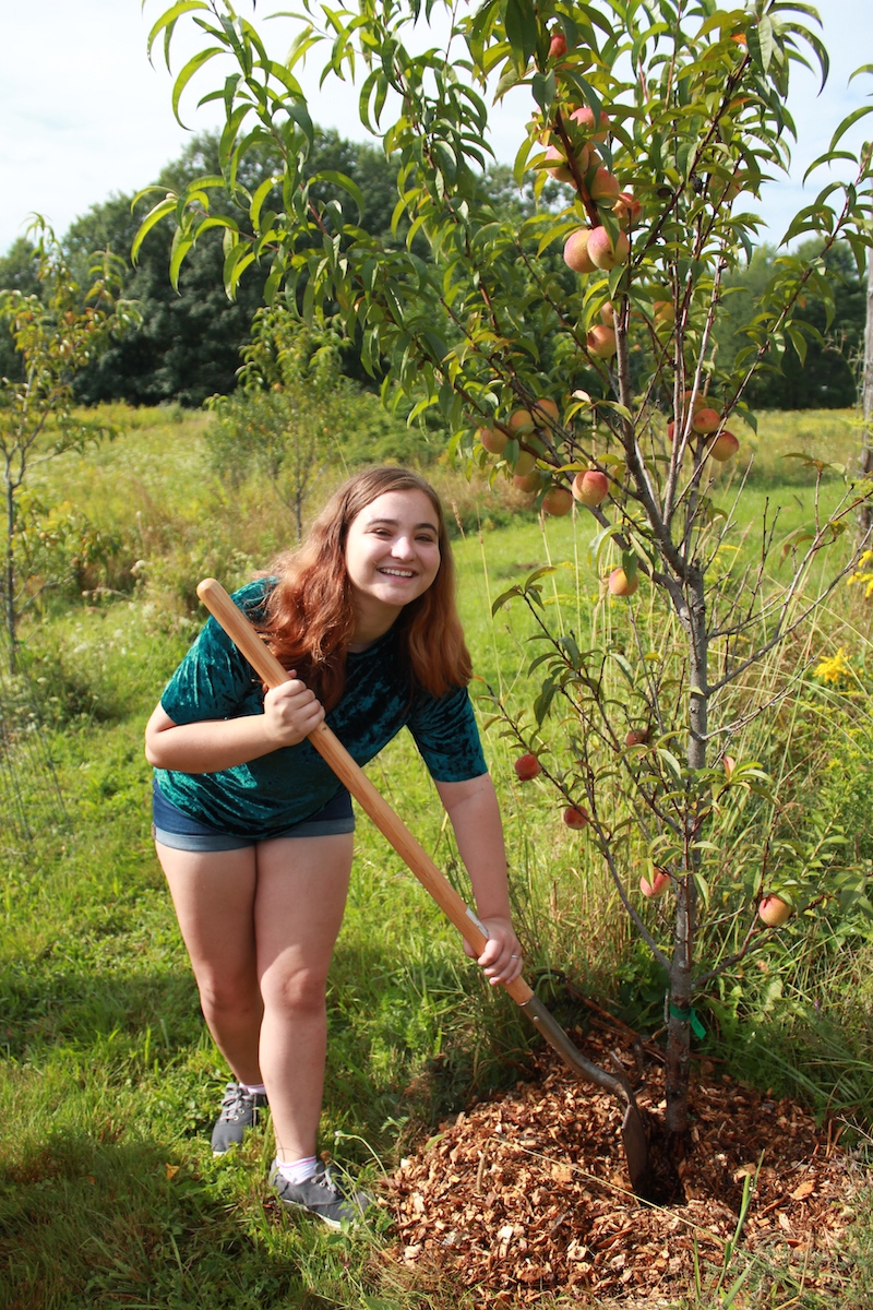 A student poses by a peach tree