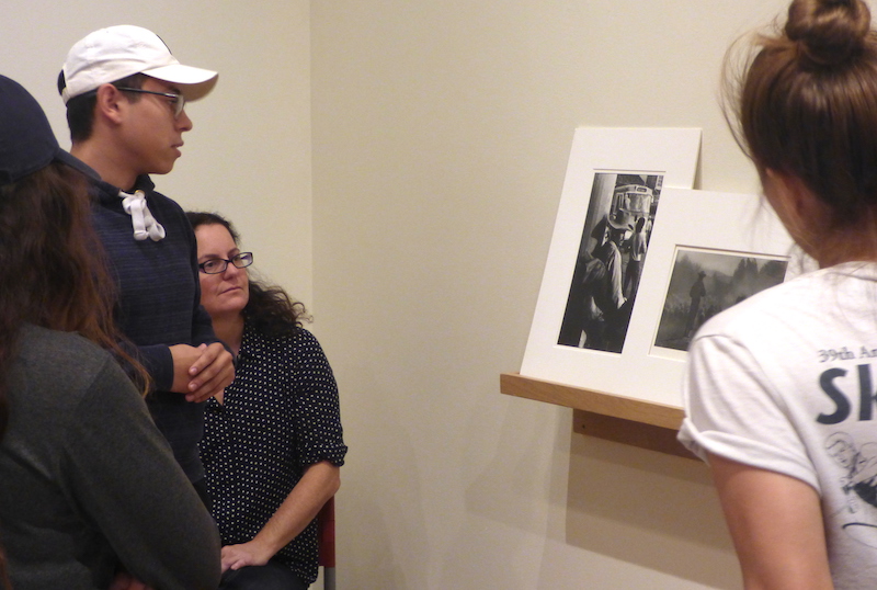 Students discussing artwork with a Roberto Bolano book in front of them