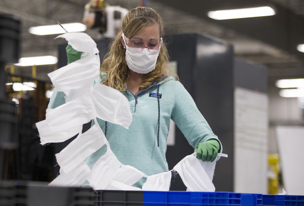 Sarah Dodson held up a string of uncut masks at the L.L. Bean plant in Brunswick, Maine.BLAKE NISSEN/FOR THE BOSTON GLOBE