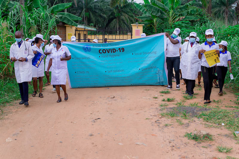 Health care workers start their walk through the village to raise awareness about Covid-19