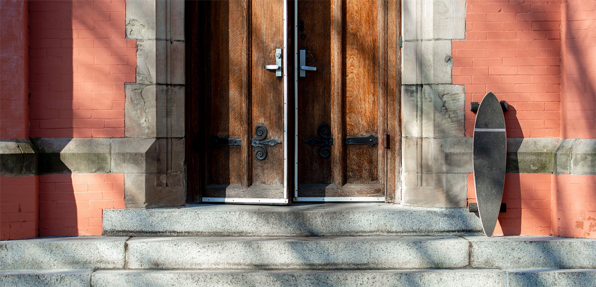 A skateboard rests near the door to Searles Hall.