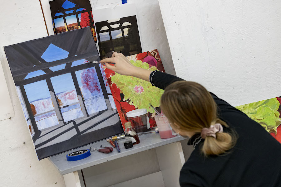 Student applying oil paint to a canvas