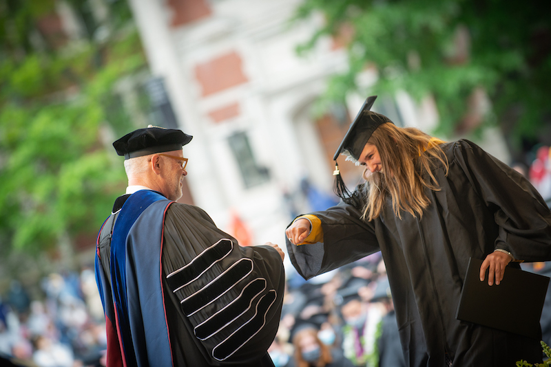 President Rose fist bumping a student during the conferring of degrees