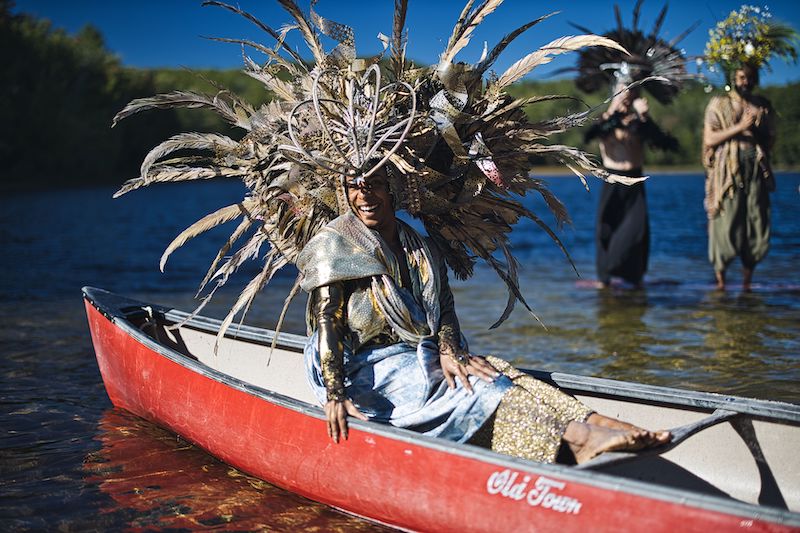 An actor in a headdress, sitting in a canoe