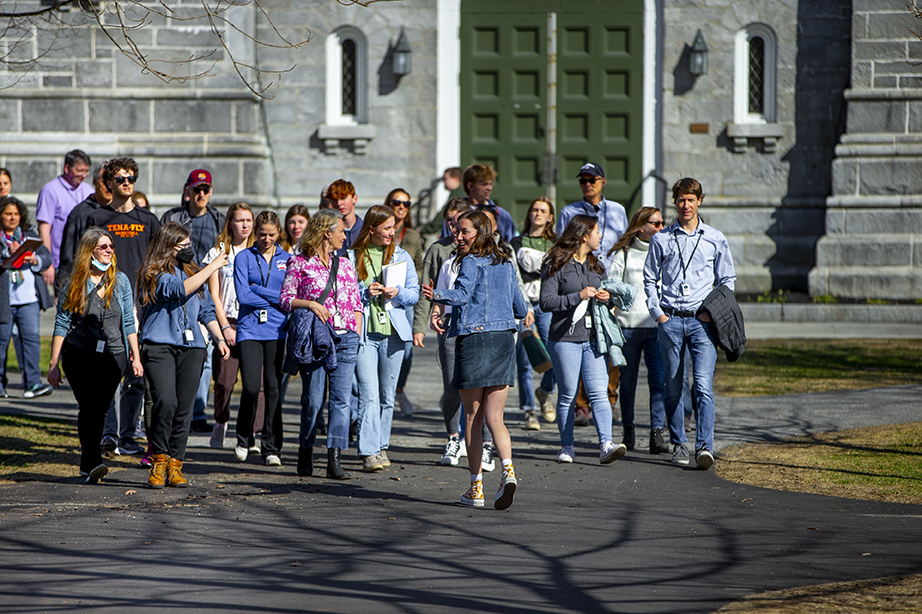 A student tour guide walking backwards towards the camera as she leads a group of admitted students and their families around campus.