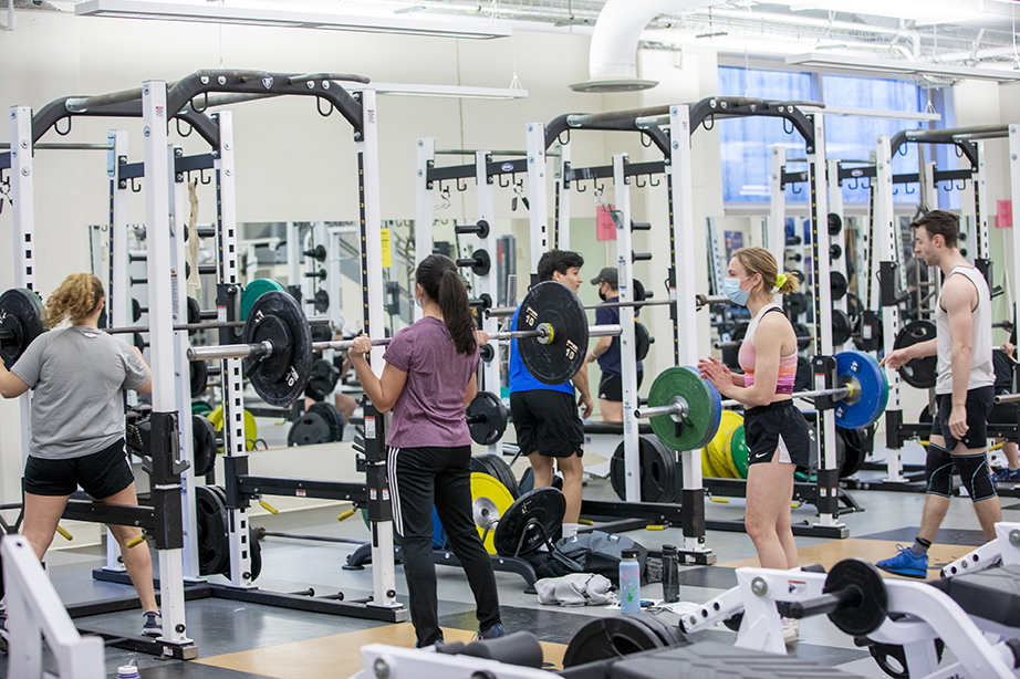 Several students in exercise clothing lifting weights and using exercise equipment in the Buck Center.