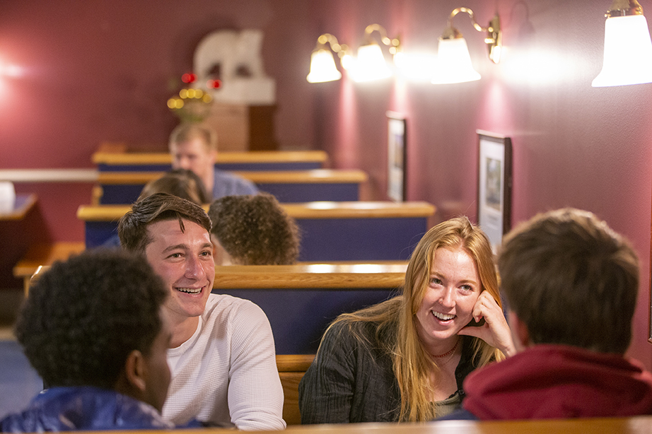 Four students sitting in a booth at Moulton Union, talking and laughing.