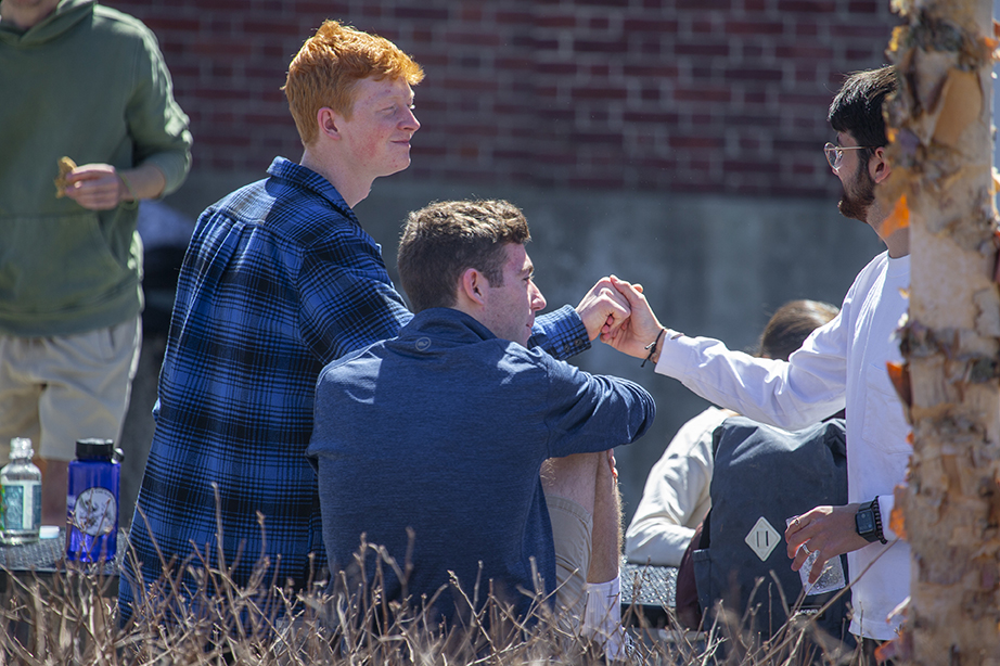 Two students clasping hands in greeting outside on campus.