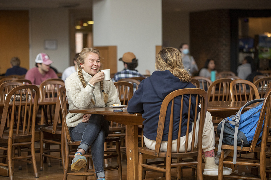 Two students sitting at a table in Thorne dining hall together and laughing.