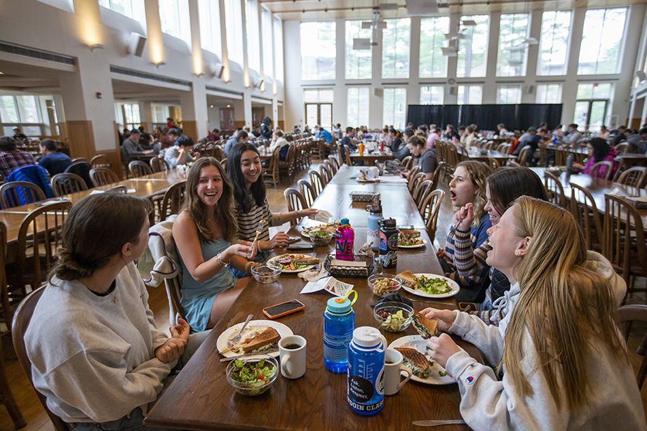 Several students sitting together at a table in Thorne dining hall, laughing.