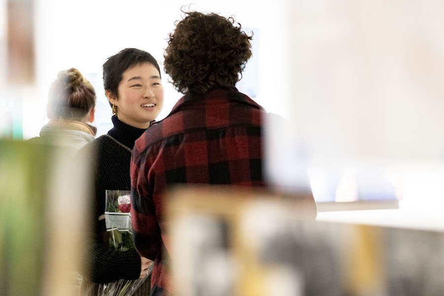 Two students talk among artworks