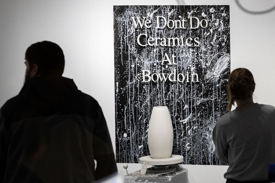A black-and-white painting saying, "We don't do ceramics at Bowdoin," behind an elegant white vase