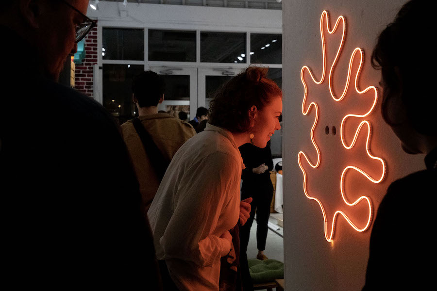 A student looks at red neon art