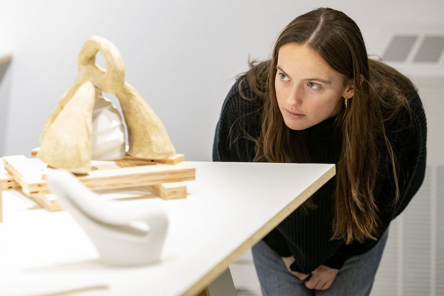 A female student peers closely at a small abstract sculpture
