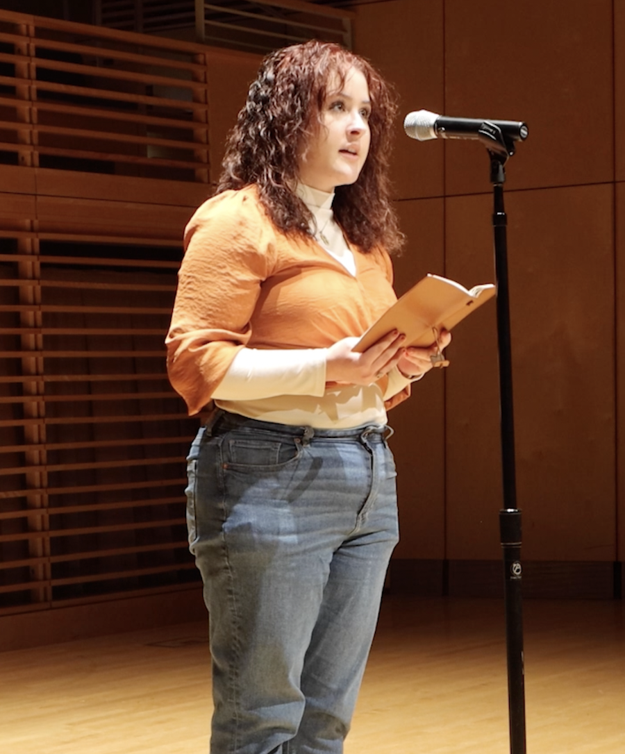 A student reads her poetry on stage