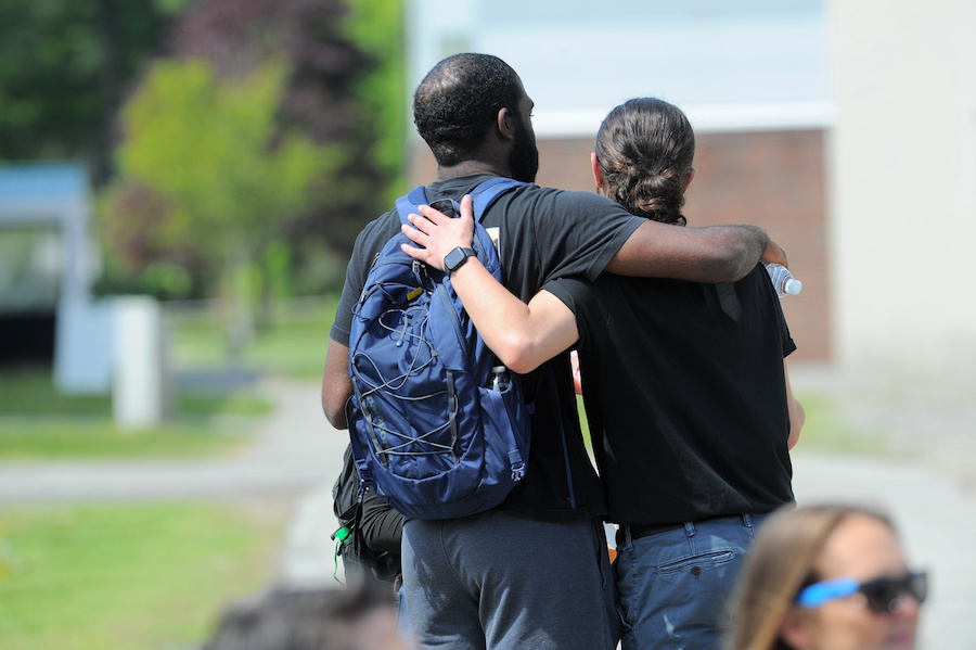 Two friends stand together, their arms on each other's backs