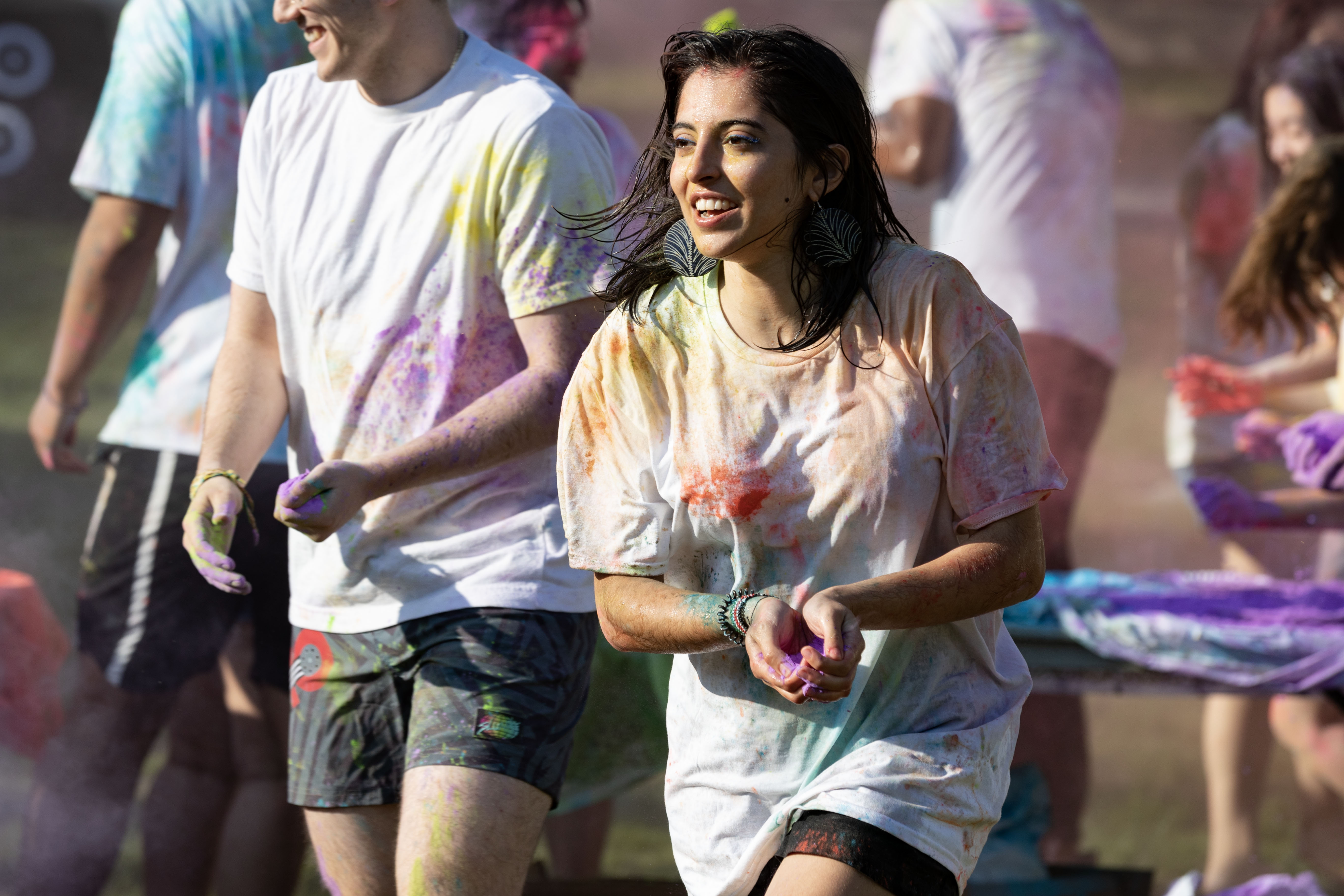 A student celebrating Holi prepares to throw pigment powder.