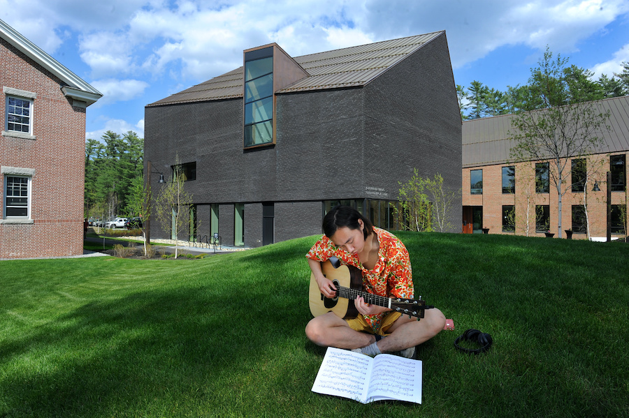 Student plays a guitar in front of the Gibbons Center