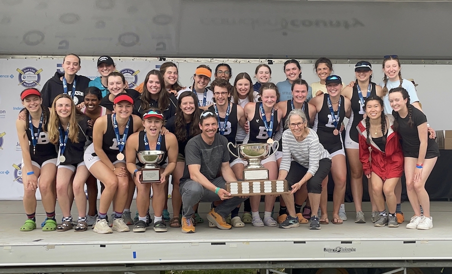 The Bowdoin women’s team with its overall points trophy, The Jack & Nancy Seitz Trophy, posing with coaches Doug Welling and Ry Hills