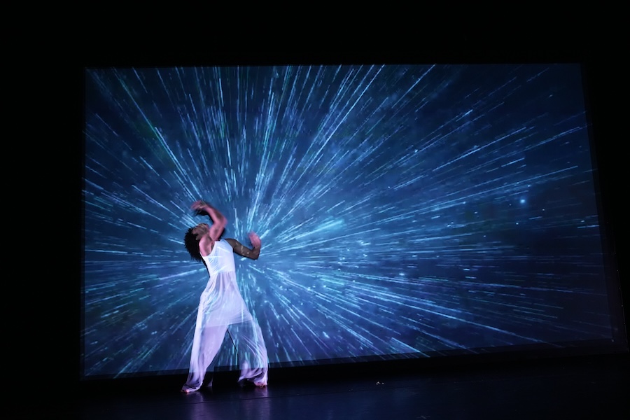 Dancing in front of video projection of universe