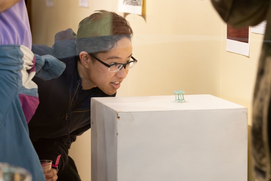 Student peers closely at a small sculpture