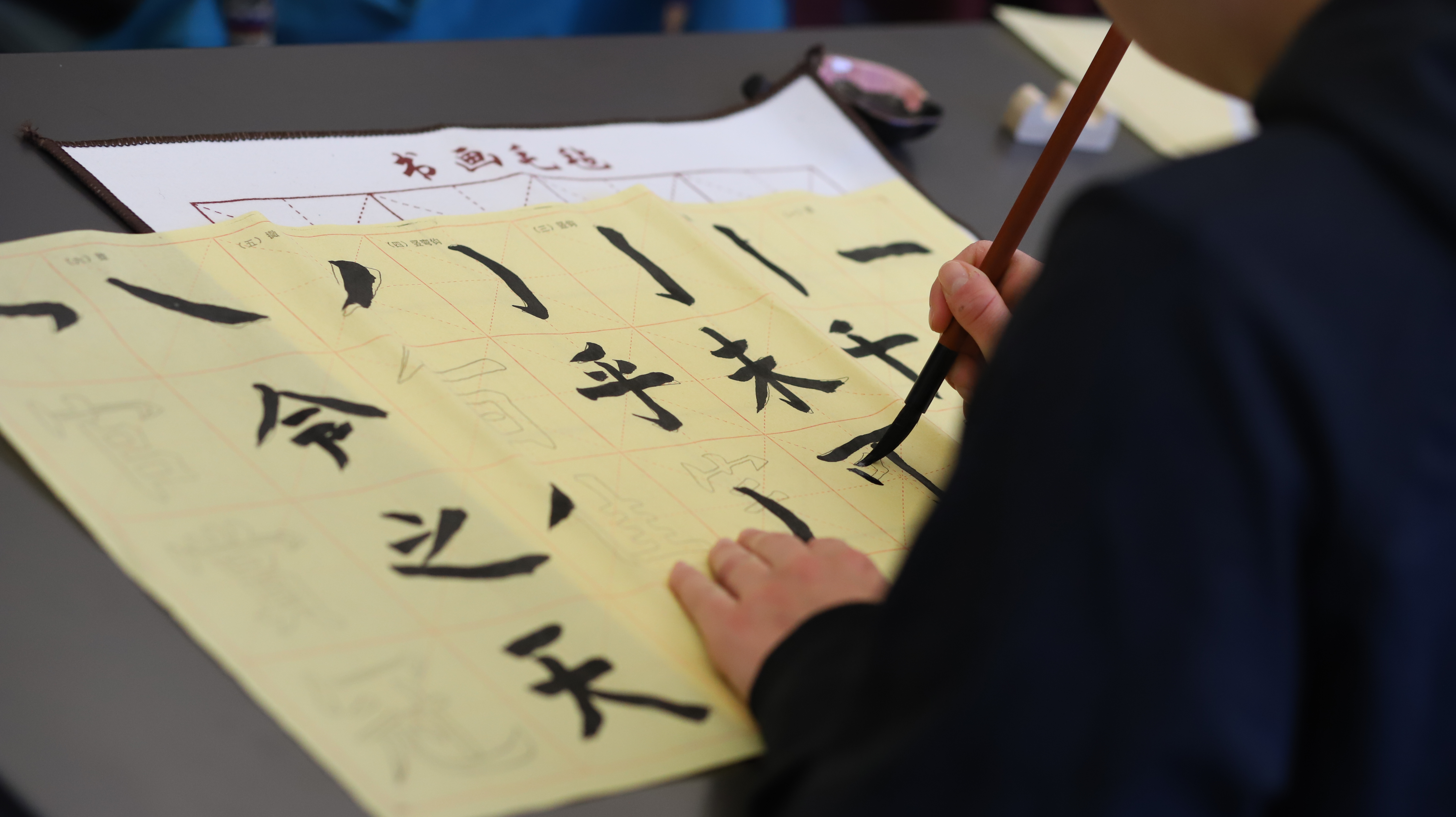 A student practices calligraphy in Brush and Ink: The Art of Writing and Painting via Calligraphy