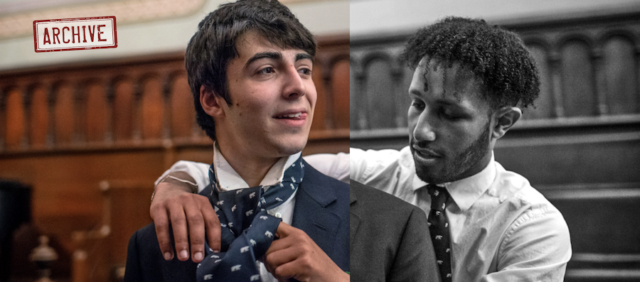 One student helps another with his tie.