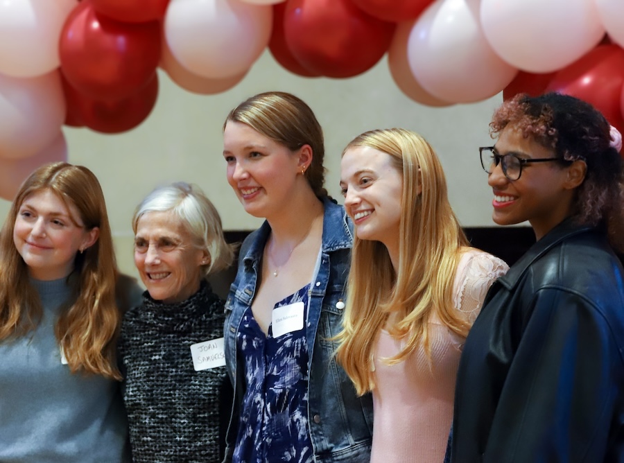 joanie benoit stands with students under balloons