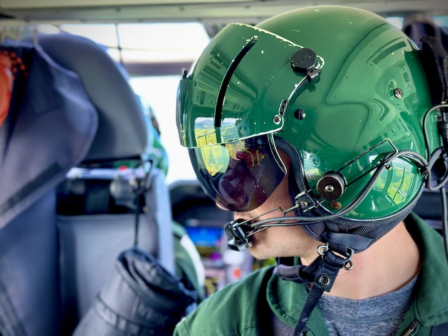 Felipe piloting the helicopter in a green helmet