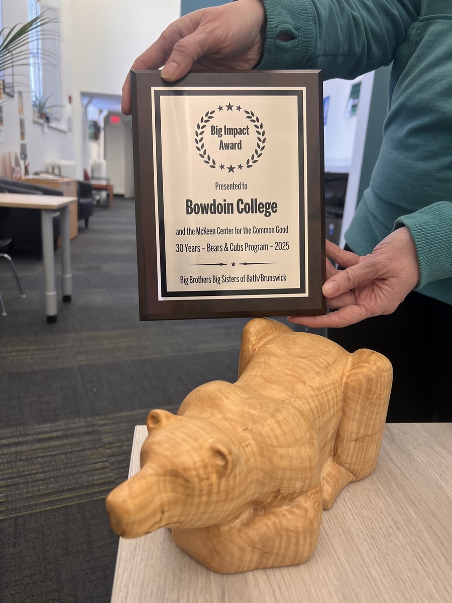 An award plaque reading: "Big Impact Award presented to Bowdoin College and the McKeen Center for the Common Good, 30 Years - Bears & Cubs Program - 2025, Big Brothers Big Sisters of Bath/Brunswick". The plaque is being held above a carved wooden statuette of a polar bear.